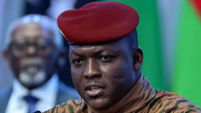 Portrait du capitaine Ibrahim Traoré en tenue militaire beige et béret rouge, symbole de la junte au pouvoir au Burkina Faso.